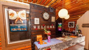 A wooden reception desk with a clock, a welcome sign, and a framed poster.