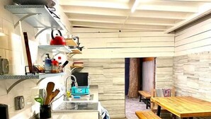 A compact kitchen with a stone-tiled floor, a wooden dining table with benches, and a built-in oven.