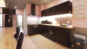 A modern kitchen with a wooden dining table, built-in appliances, and a motivational quote on the wall. - Hevals Grand Schöneberg (Berlin)