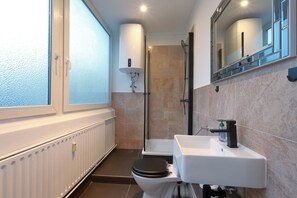 A modern bathroom with a toilet, sink, and shower. - Hevals Grand Schöneberg (Berlin)
