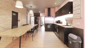 A modern kitchen with a wooden dining table and chairs, a built-in oven, and a sink. - Hevals Grand Schöneberg (Berlin)