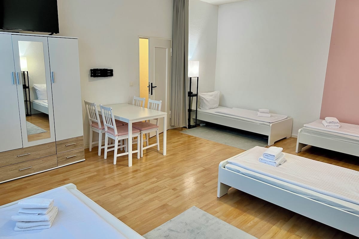 A hotel room with a bed, a desk with chairs, a wardrobe, and a TV.