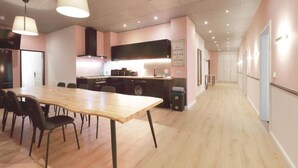A modern kitchen with a wooden table and chairs, a built-in stove, and a sign about happiness. - Hevals Grand Schöneberg (Berlin)