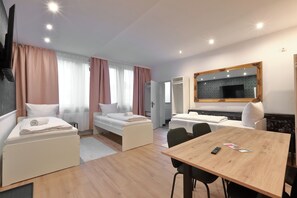 A modern hotel room with two single beds, a wooden dining table, and a large mirror. - Hevals Grand Schöneberg (Berlin)