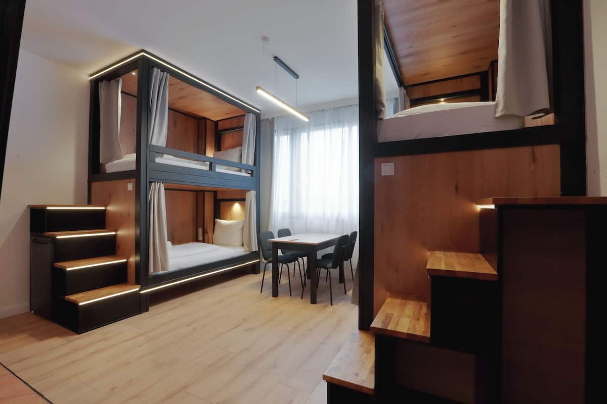A modern, compact room with a bunk bed, a desk, and a chair.