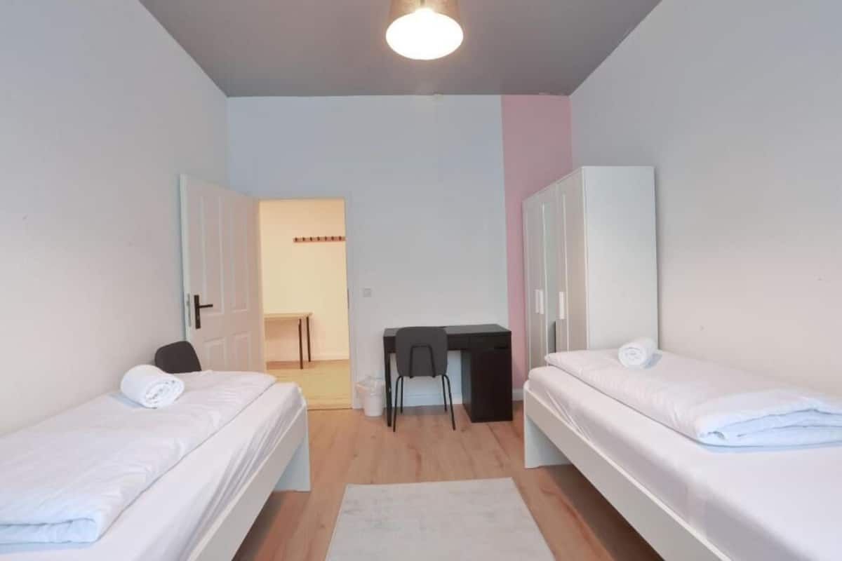 A bedroom with two single beds, a desk, and a chair.