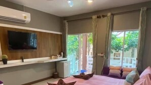 A modern bedroom with a large bed, a ceiling fan, a flat-screen TV, and a window with curtains. - Bee Orchid Pool Villa (Koh Lan)