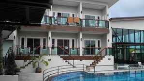 A modern hotel with a swimming pool, multiple balconies, and a covered outdoor area. - Bee Orchid Pool Villa (Koh Lan)