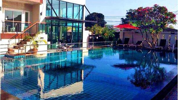 A modern building with a glass facade, a swimming pool, and outdoor seating areas. - Bee Orchid Pool Villa (Koh Lan)