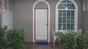 A hallway with a white door, a window with a white frame, and two white chairs. - Bee Orchid Pool Villa (Koh Lan)