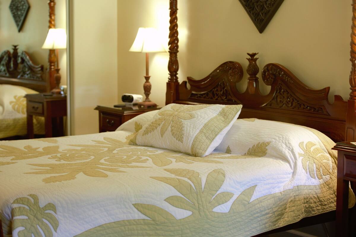 A neatly made bed with a floral bedspread and a wooden headboard.
