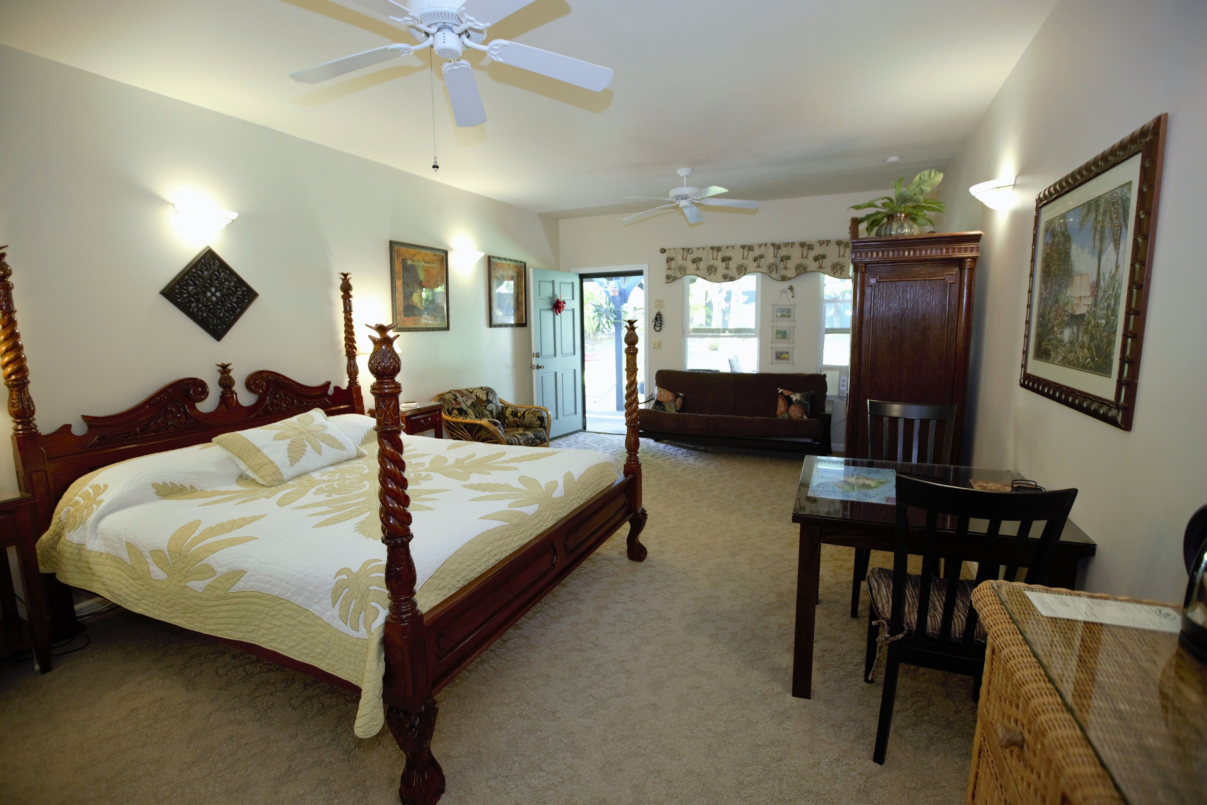 A bedroom with a four-poster bed, a desk, and a dining table.