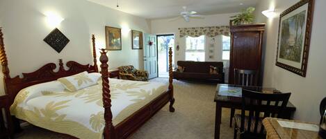 A bedroom with a four-poster bed, a desk, and a dining table.