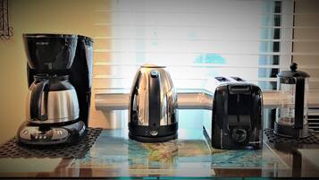 A coffee maker, a toaster, and a grinder on a table with a map underneath.