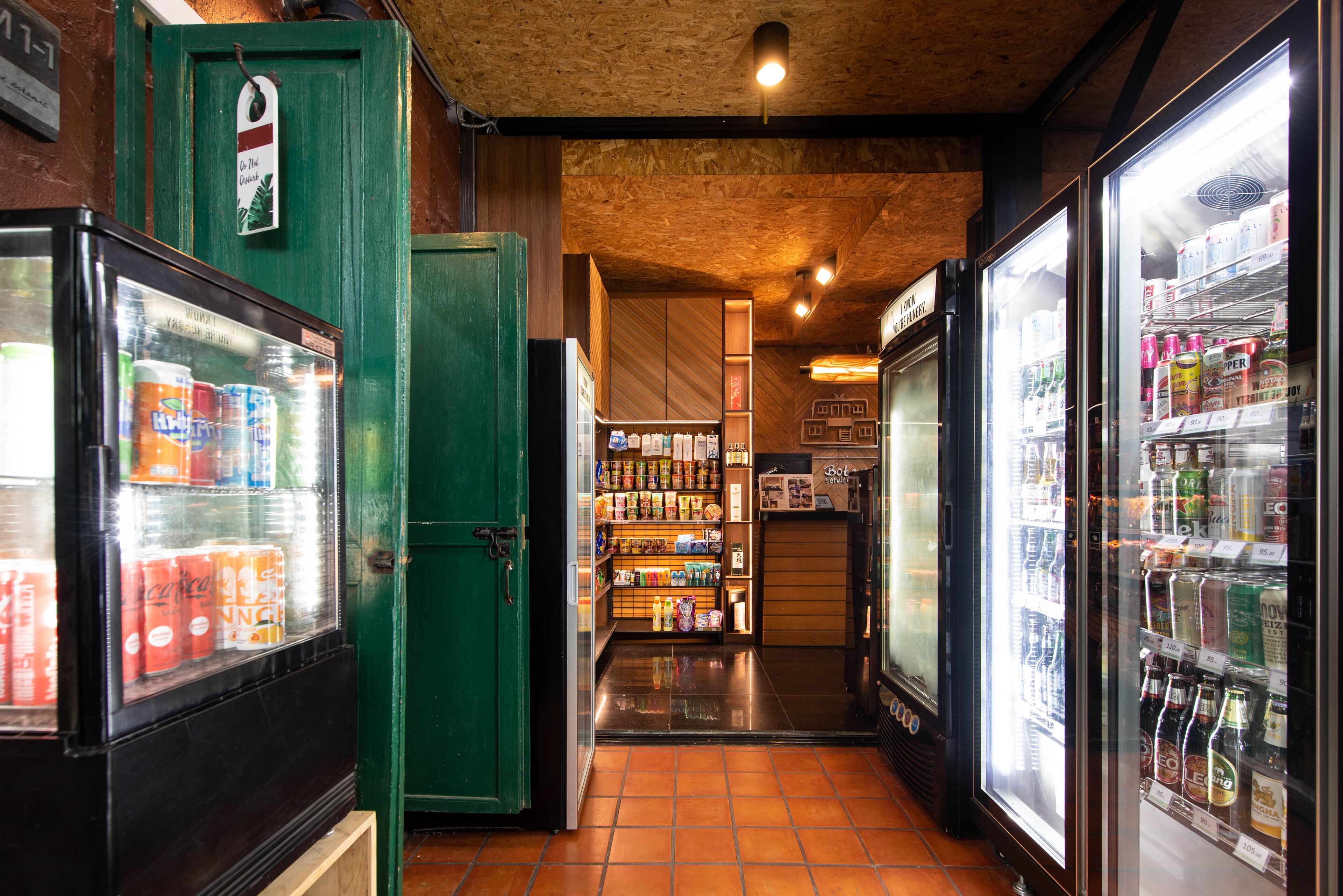 A corridor with refrigerated beverage dispensers and a green door.
