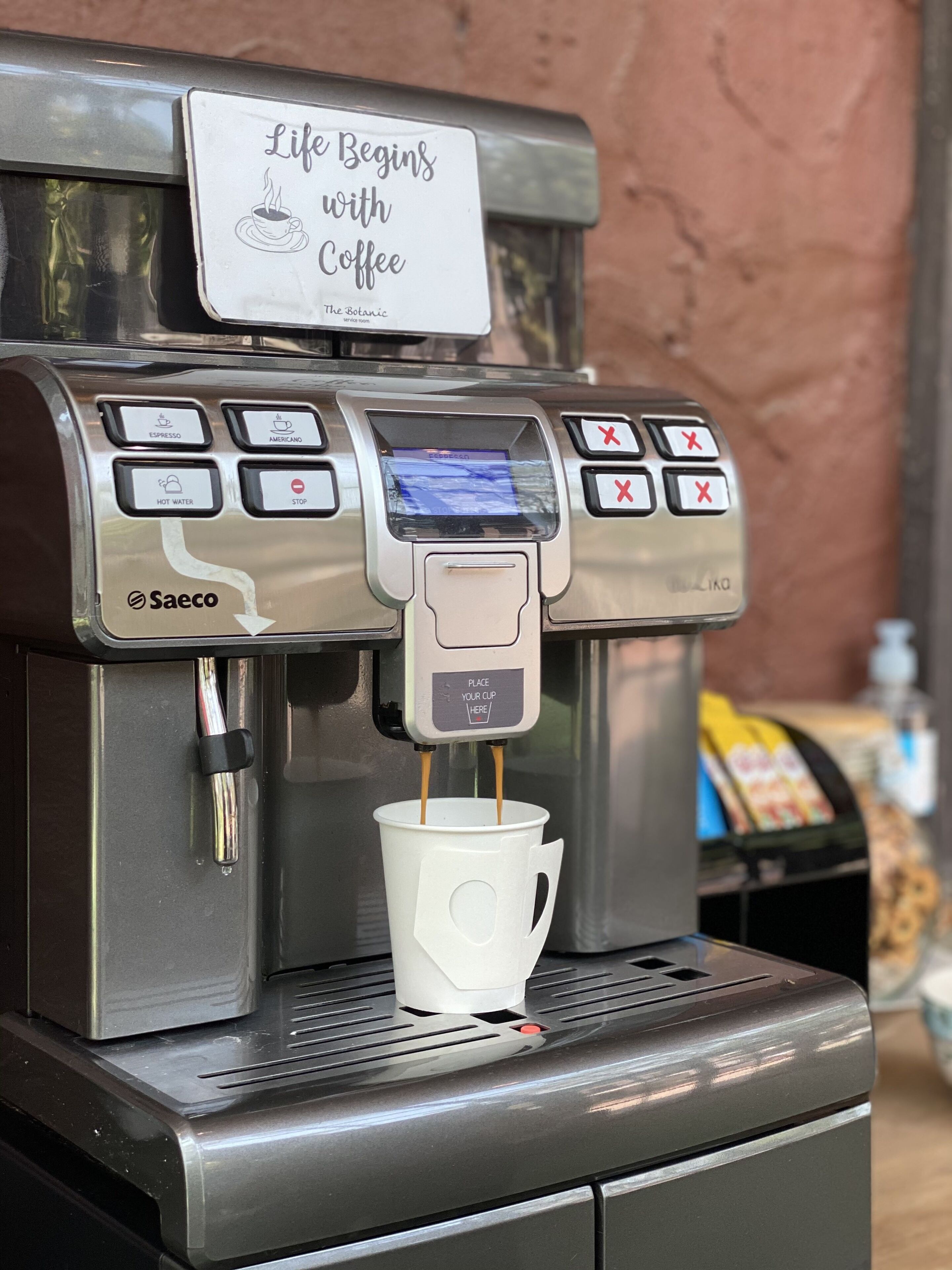 A coffee machine with a sign that reads "Life Begins with Coffee" and options for espresso, americano, and hot water.