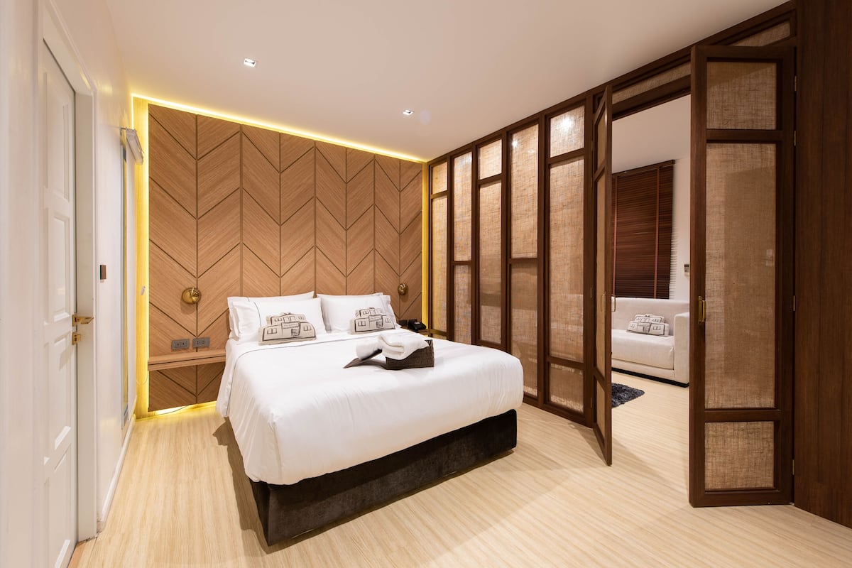 Ein modernes Schlafzimmer mit einem großen Bett, einer Wand aus Holzpaneelen und einer Schiebetür zum Badezimmer.