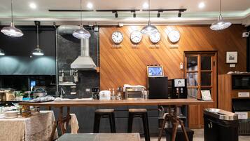 Una cocina moderna con detalles de madera, una isla central con taburetes y relojes que marcan la hora en distintas ciudades.