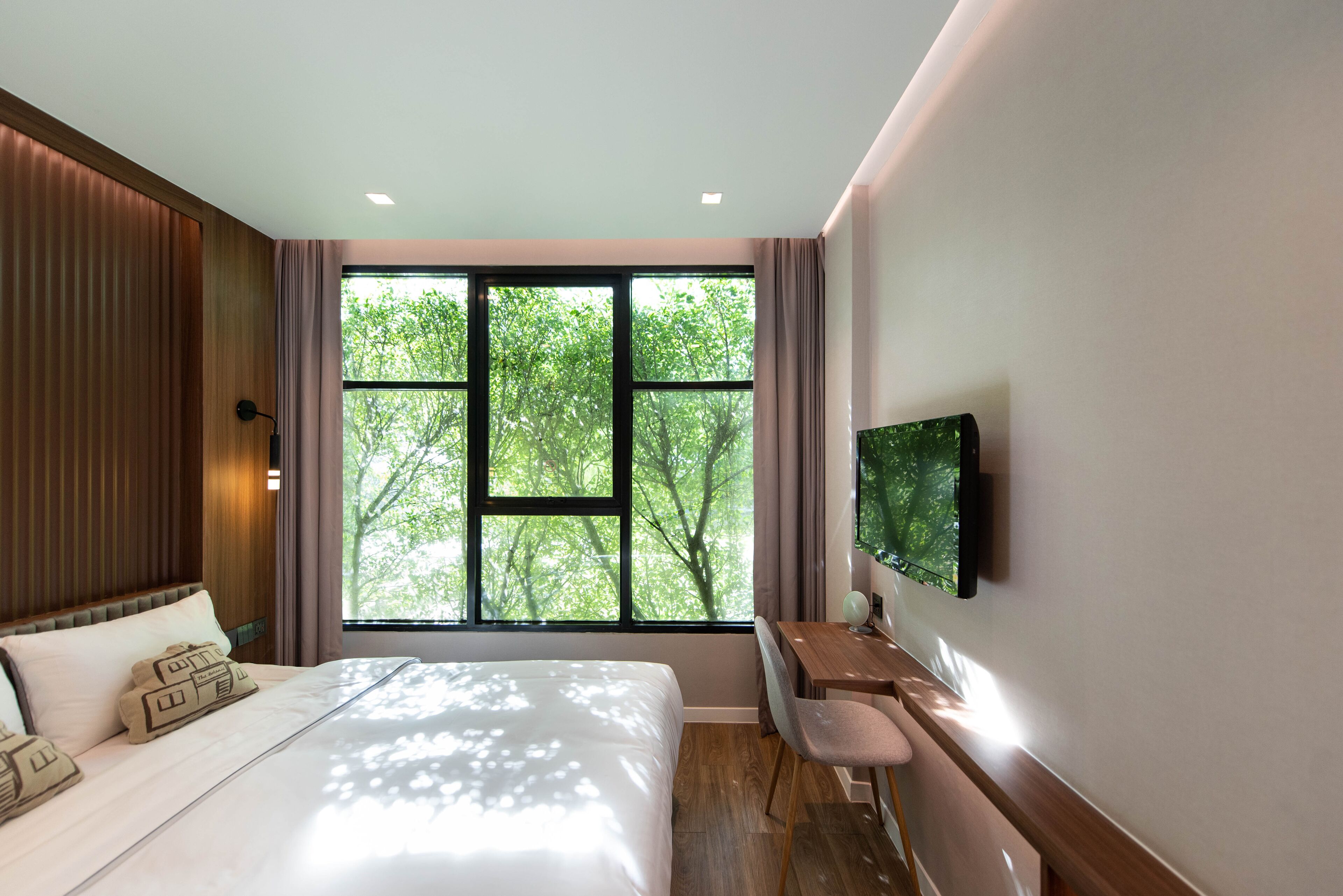 A modern hotel room with a large bed, a desk, and a TV.