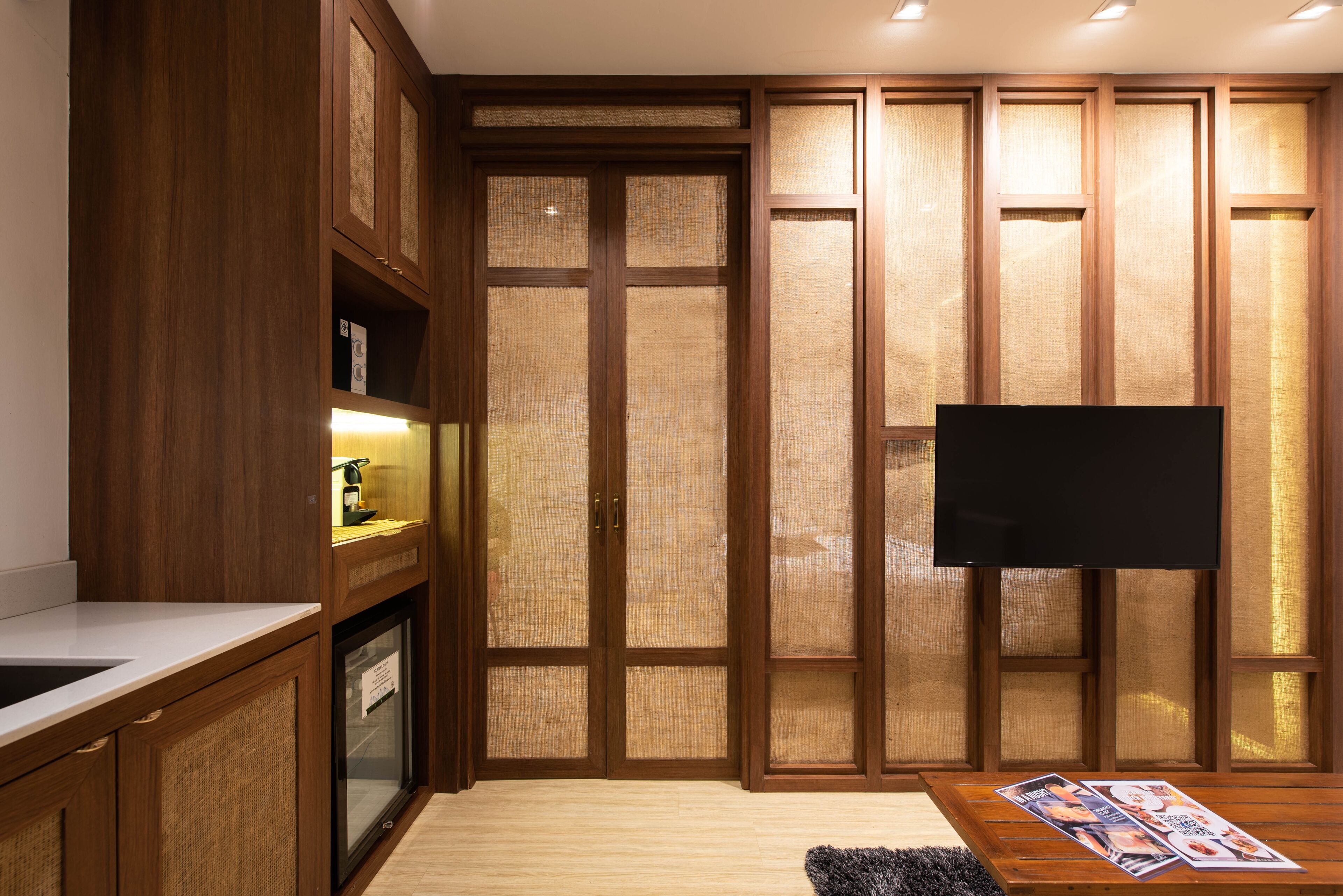 A modern kitchen with wooden cabinets, a built-in oven, and a flat-screen TV mounted on the wall.