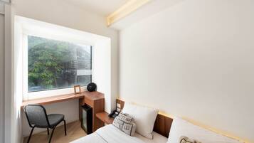 A modern hotel room with a desk, chair, and bed.