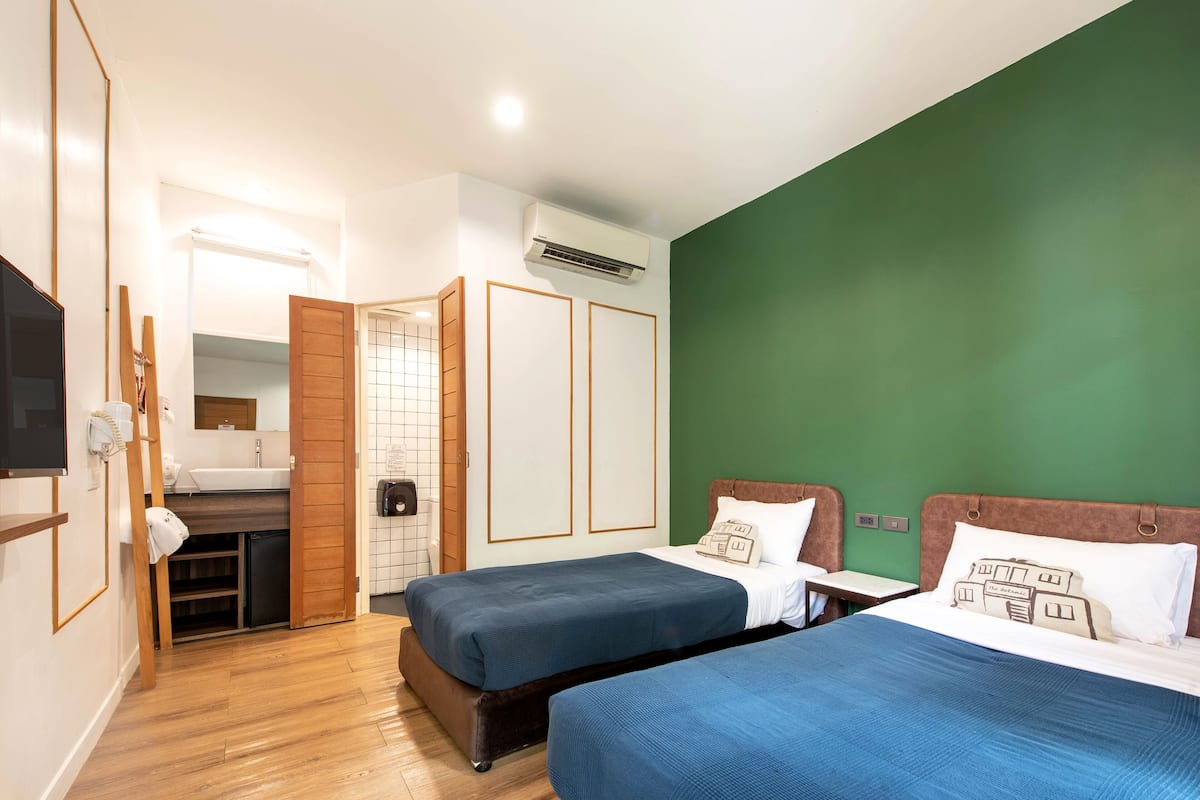Ein Hotelzimmer mit zwei Betten, einer kleinen Küchenzeile und einer Wand in Grünton.