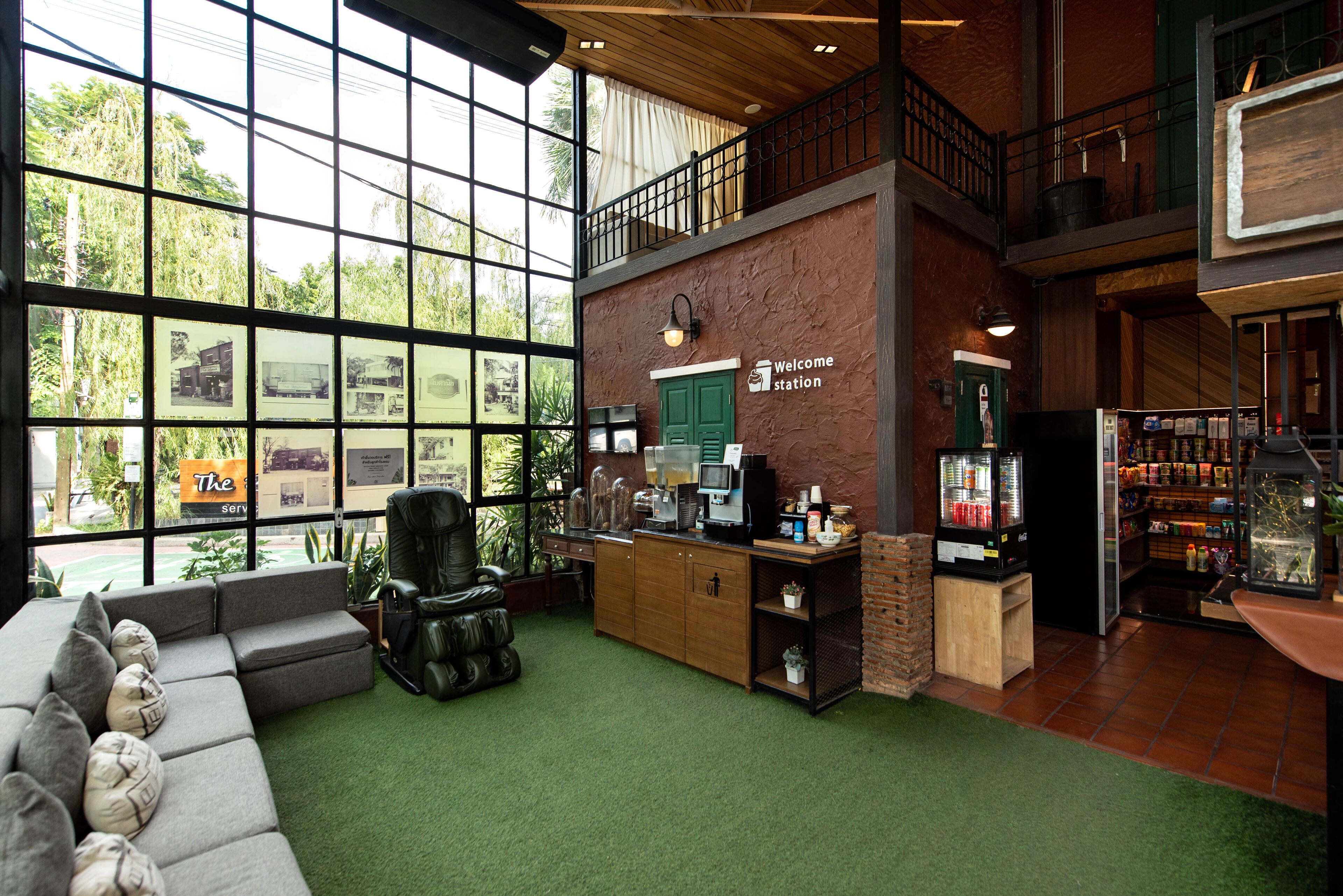 A spacious lobby with a large window, a reception desk, a seating area, and a staircase leading to an upper level.