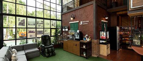 A spacious lobby with a large window, a reception desk, a seating area, and a staircase leading to an upper level.