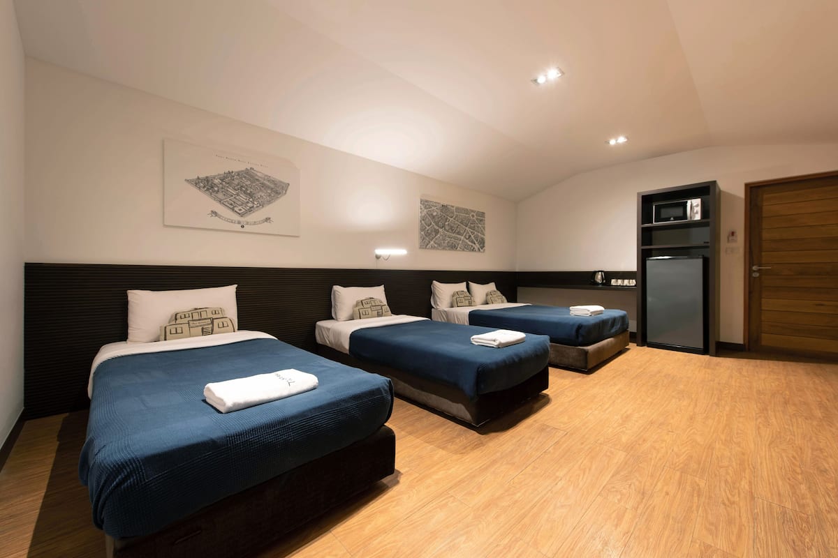 Ein Hotelzimmer mit drei Betten, einer Mikrowelle und einem Kühlschrank.
