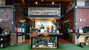 A reception area with a sign reading "The Botanica Service Room," a green door, a counter with various items, and a small plant display. - The Botanic Service Room (Pak Kret)