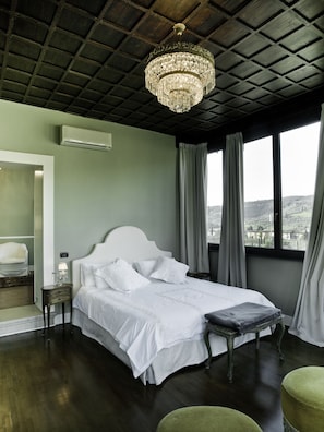 A bedroom with a large bed, a nightstand, a chair, and a view of the outdoors through a window. - Residenza Borgo 27 (Grezzana)