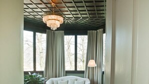 Una habitación con un sofá blanco, dos otomanas, una mesa con lámpara y un candelabro.