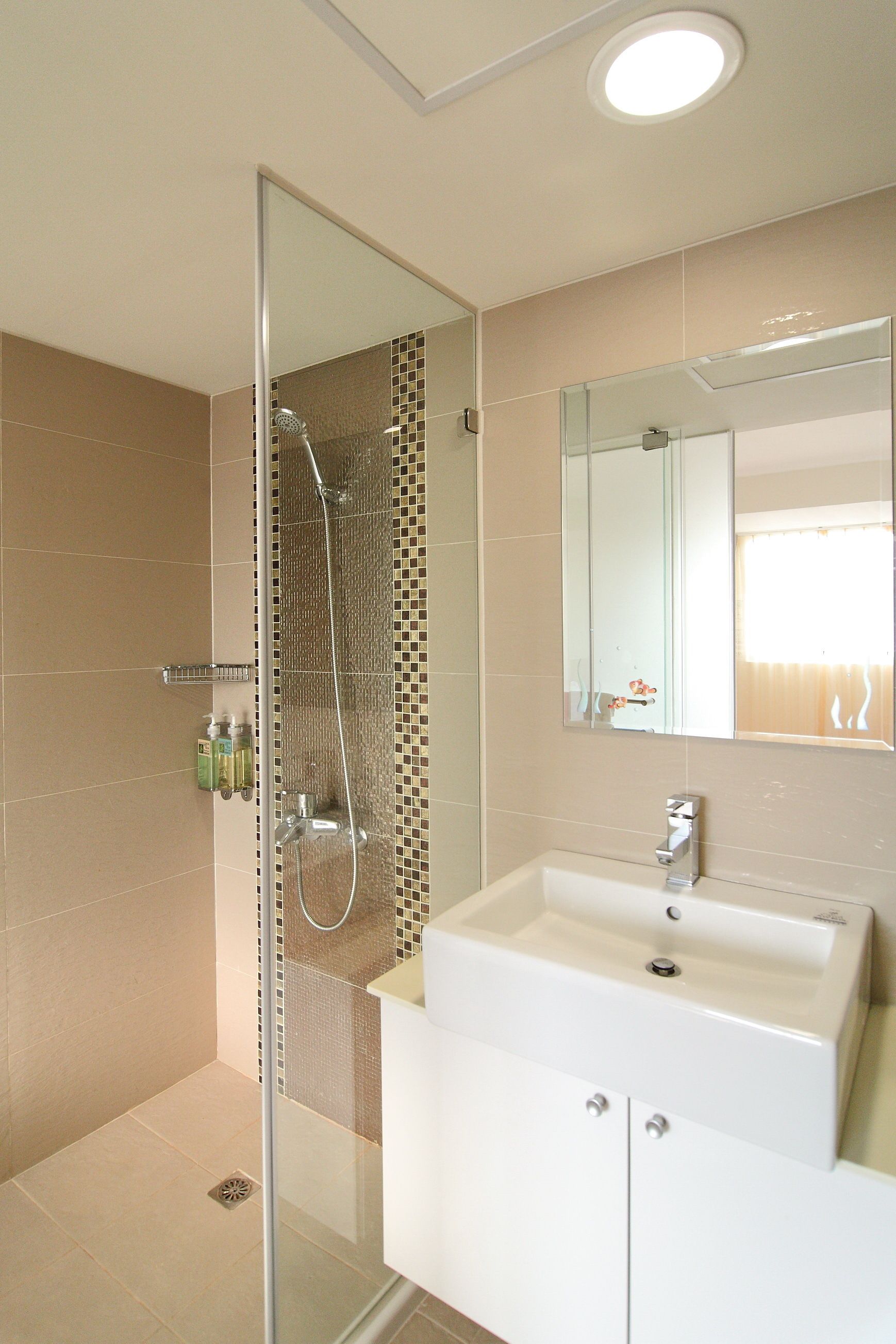 A modern bathroom with a glass-enclosed shower, a white sink, and a large mirror.
