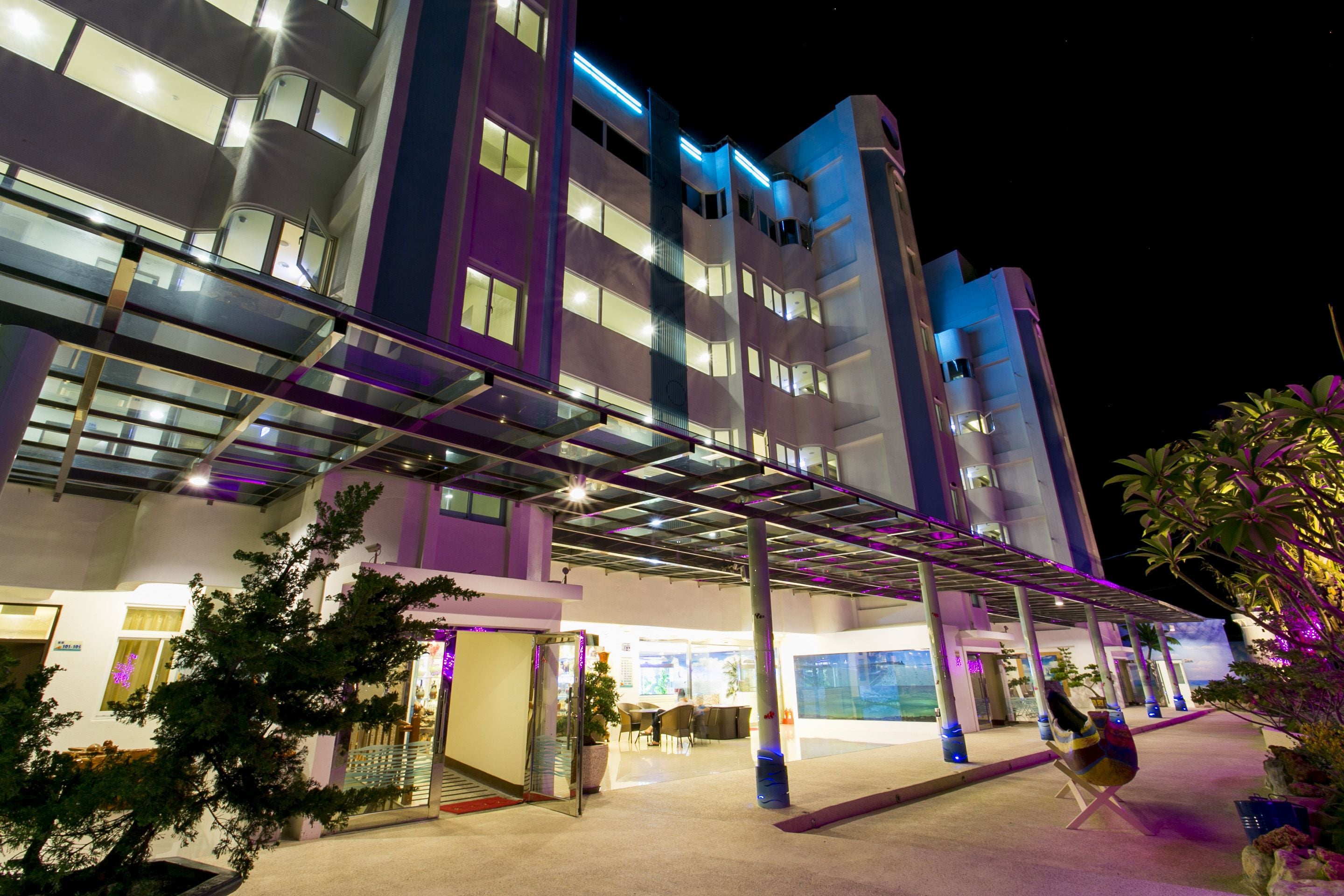A modern hotel with a covered entrance, multiple floors, and a glass facade.