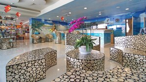 A lobby with circular seating, a reception desk, and a wall mural. - Clownfish Resort (Hengchun)