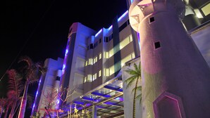 A modern hotel with a cylindrical tower, multiple balconies, and palm trees. - Clownfish Resort (Hengchun)