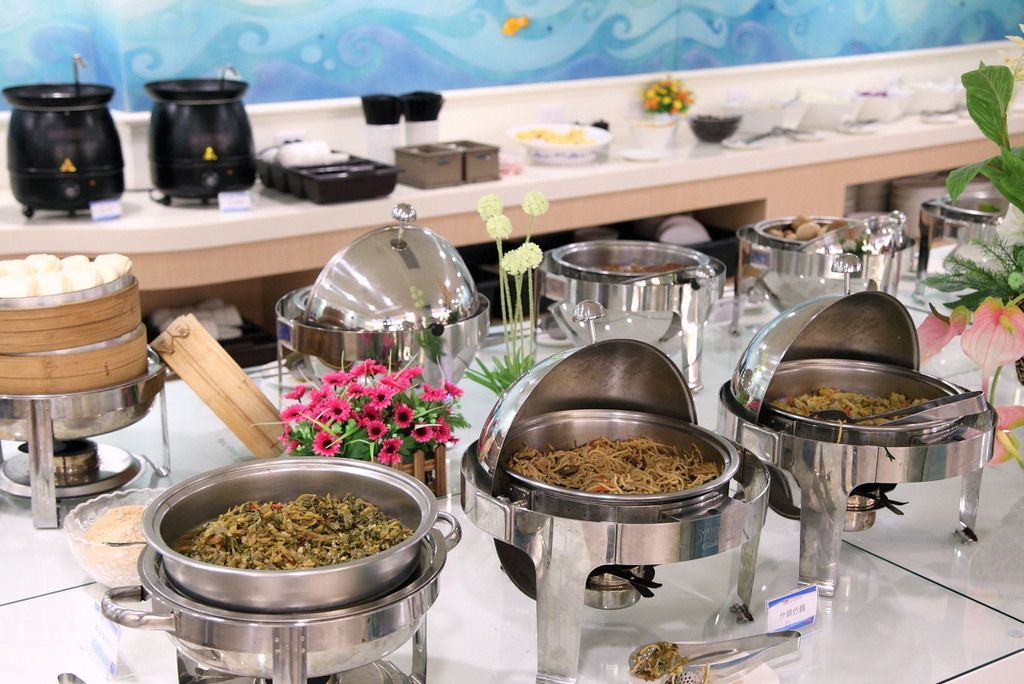 A buffet setup with various food containers and a decorative flower arrangement.