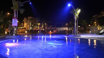 Relax by the serene pool surrounded by palm trees.