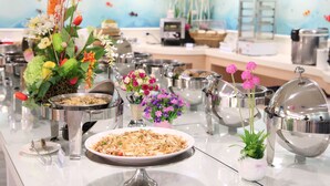 A buffet setup with various dishes, a coffee machine, and decorative flowers. - Clownfish Resort (Hengchun)