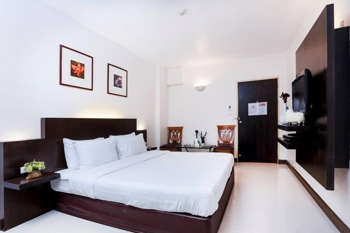 Habitación de hotel con una cama grande, un televisor, un escritorio y una silla.