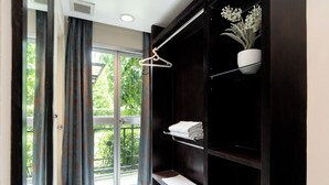 Una habitación moderna con puerta corrediza de vidrio que da a un balcón, un armario de madera oscura con estantes y una lámpara colgante.