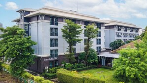 Un hotel moderno con varios pisos, amplias ventanas y un jardín bien cuidado.