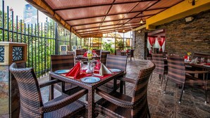 An outdoor dining area with wicker furniture and a covered patio. - The Monarch Hotel (Nairobi)