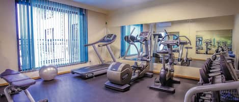 Un gimnasio con cintas de correr, elípticas y una máquina de remo.