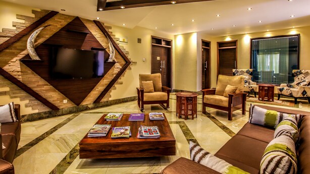 A spacious living area with a modern staircase, comfortable seating, and a flat-screen TV. - The Monarch Hotel (Nairobi)