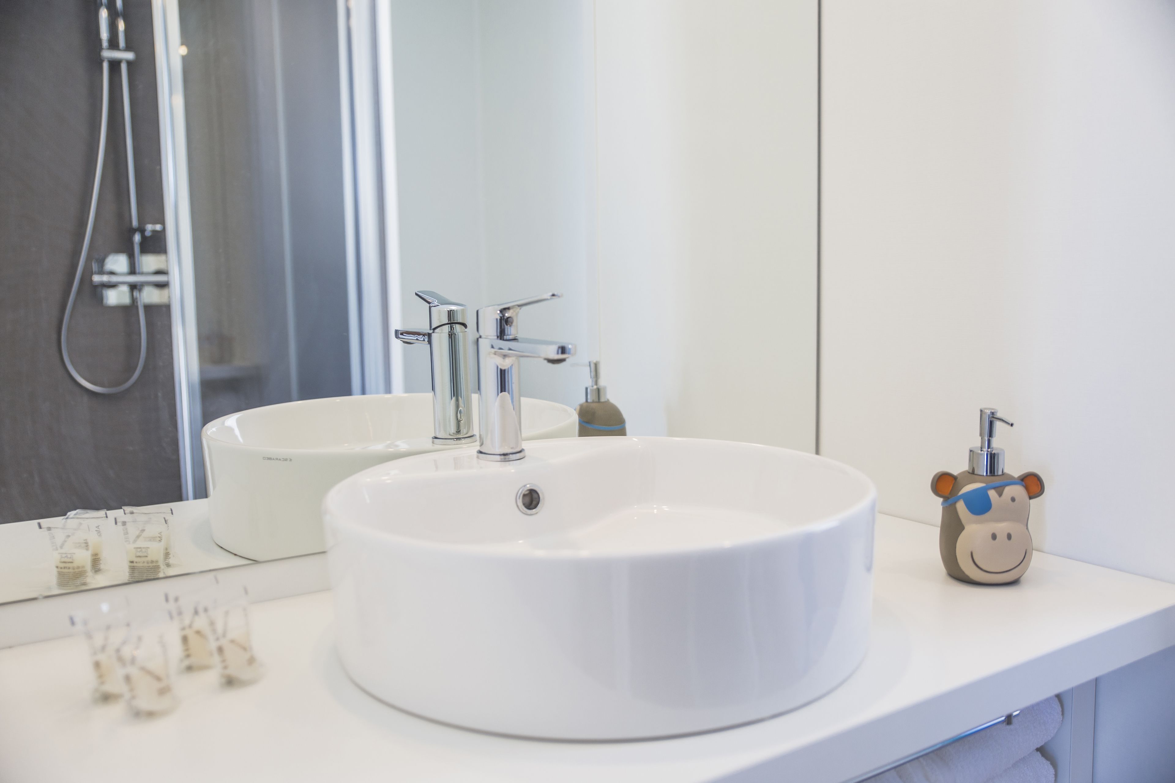 A bathroom with a large white sink, a mirror, and a shower.