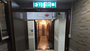Un pasillo con una señal de salida, una cámara de seguridad y una pared iluminada.