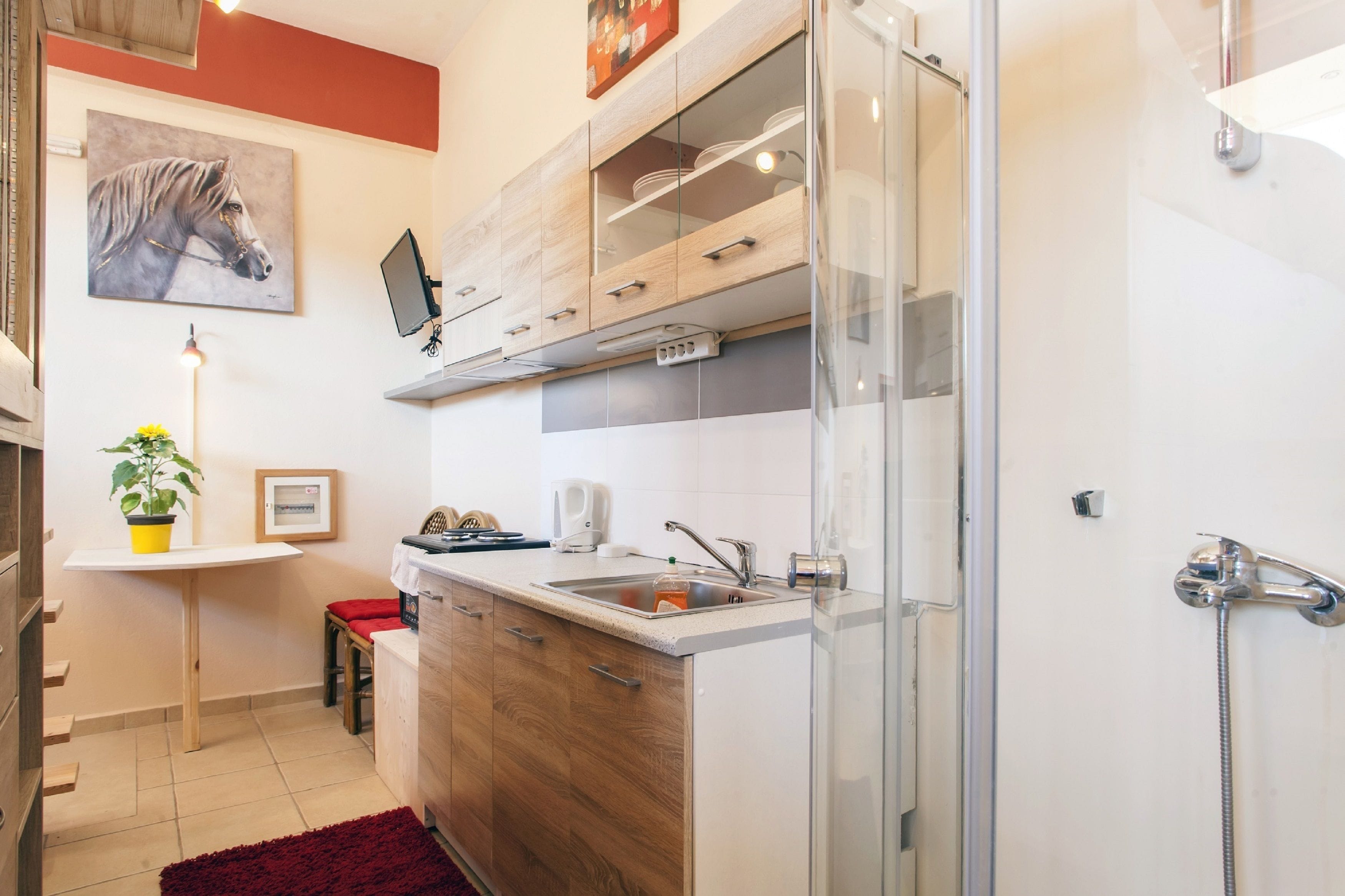 A compact kitchen with a sink, countertop, and cabinets.