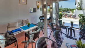 A covered outdoor seating area with wooden beams, a blue table, and black chairs. - Valentina apartments (Hersonissos)