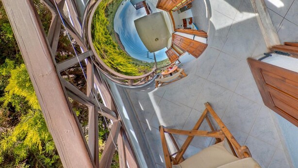 A circular outdoor seating area with a central table and chairs, surrounded by wooden beams and glass walls, offering a view of the surrounding greenery. - Valentina apartments (Hersonissos)